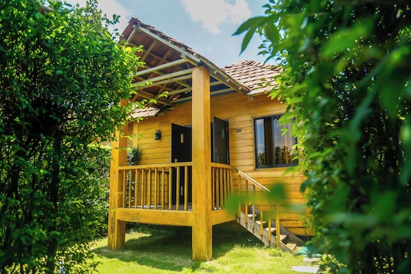 A wooden cabin with a porch, a staircase, and a window.