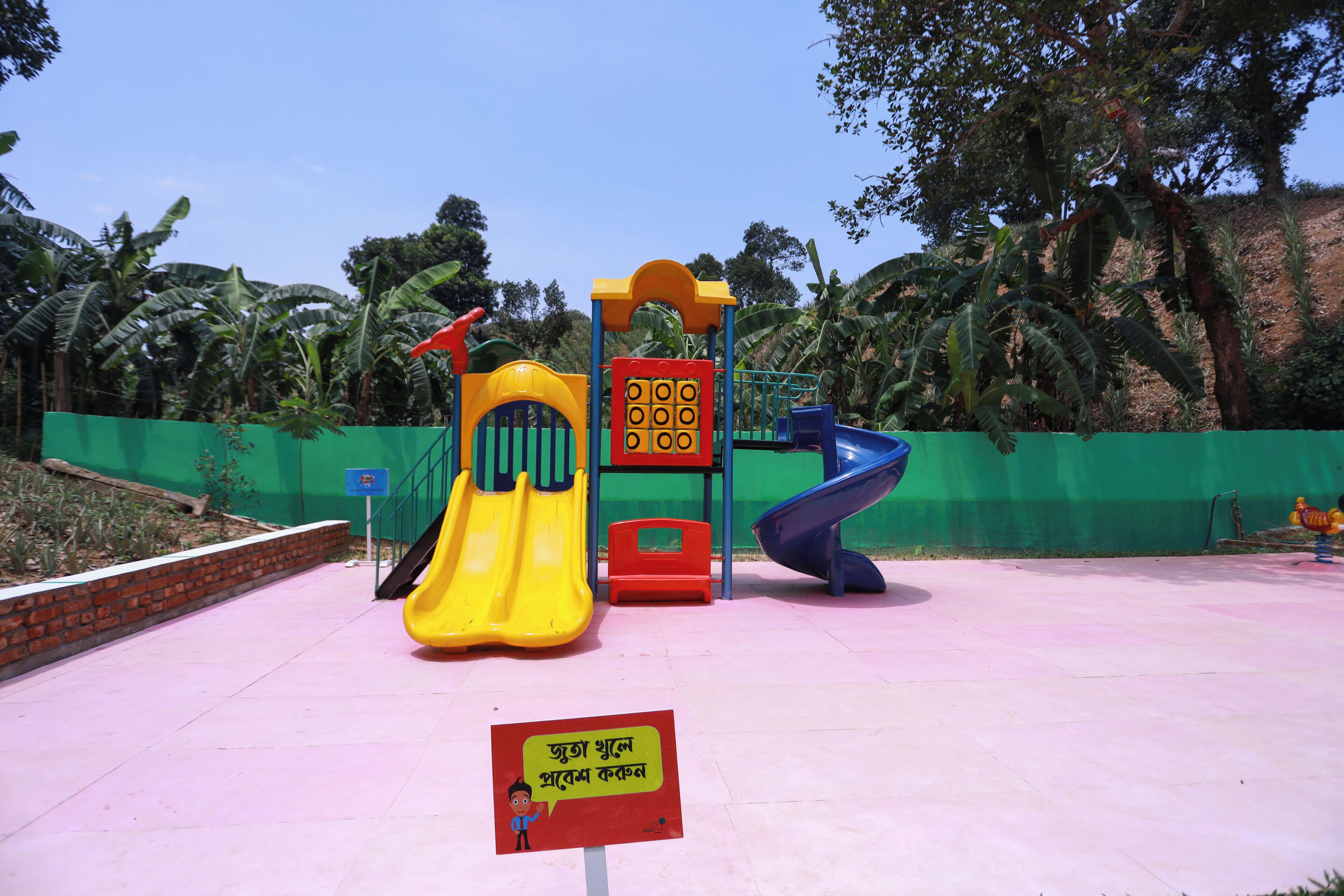 A playground with a yellow slide, a blue slide, and a climbing structure.