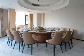 Een vergaderruimte met een ronde tafel, beige stoelen en een decoratief middelpunt.