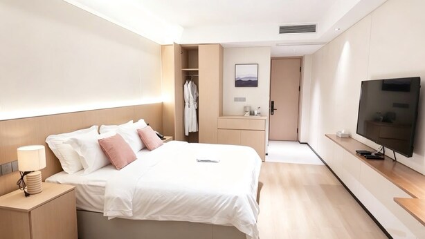 A modern hotel room with a bed, bedside table, TV, and a walk-in closet. - Ebony Hotel (Douala)