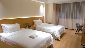A hotel room with two beds, a desk, a chair, and a large window with curtains. - Ebony Hotel (Douala)