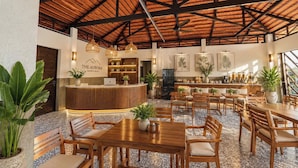 A spacious indoor area with a high ceiling, wooden reception desk, multiple seating arrangements, and decorative plants. - The Aurora Retreat (Phu Quoc)