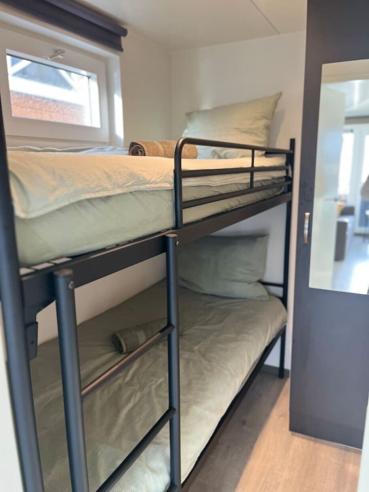A bunk bed with a window above the top bunk.
