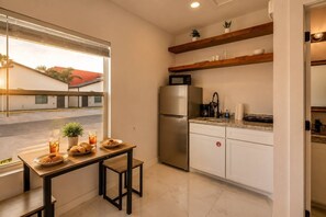 Eine kompakte Küche mit Kühlschrank, Mikrowelle und Holzregalen über der Arbeitsfläche.