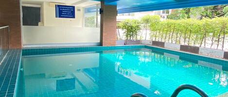 An indoor swimming pool with clear blue water, a tiled floor, and a blue ceiling.
