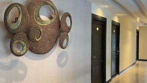 A modern hallway with a textured wall art installation and a series of doors. - Leelawadee Huaikhwang (Bangkok)