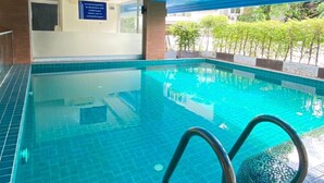 An indoor swimming pool with clear blue water, a tiled floor, and a blue ceiling. - Leelawadee Huaikhwang (Bangkok)