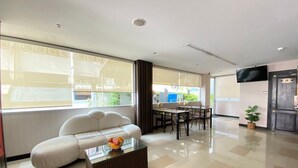 A modern living room with a sofa, a glass coffee table, a dining table with chairs, and a TV mounted on the wall. - Leelawadee Huaikhwang (Bangkok)