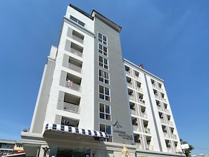 Um hotel com vários andares, varandas e uma placa indicando ser um hotel.