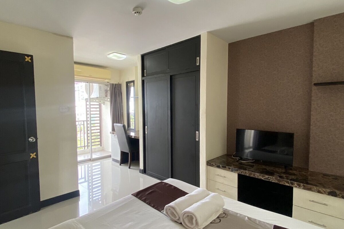 A hotel room with a bed, a TV, a desk, and a wardrobe.