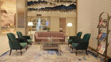 A lobby with a sofa, chairs, a coffee table, and a patterned wall.