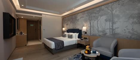 Una habitación de hotel con una cama, un rincón de estar con una mesa y un televisor de pared.