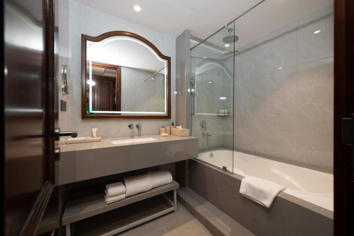 A modern bathroom with a glass-enclosed shower, a large mirror, and a bathtub.