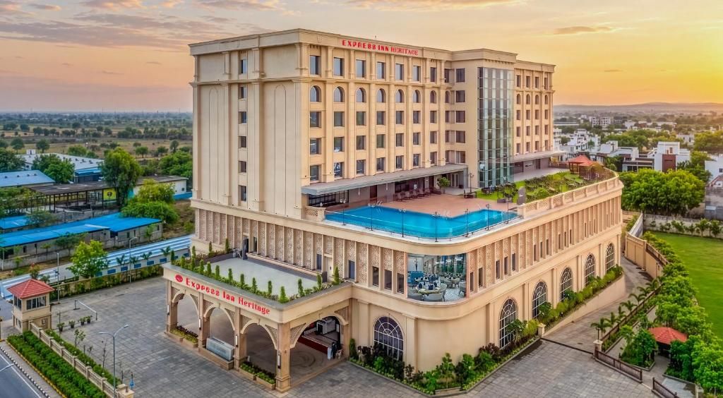 A hotel with a pool, multiple floors, and a large entrance.