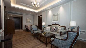 A spacious living room with a sofa, armchairs, a coffee table, and a chandelier.