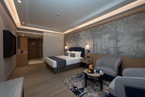 Una habitación de hotel con una cama, un rincón de estar con una mesa y un televisor de pared.
