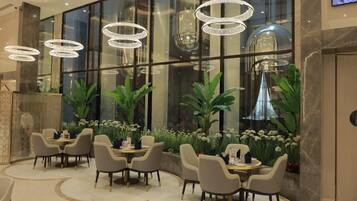 A modern hotel lobby with round tables, comfortable seating, and large windows.