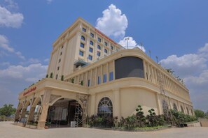 Un hotel con una entrada amplia, varios pisos y un letrero llamativo.