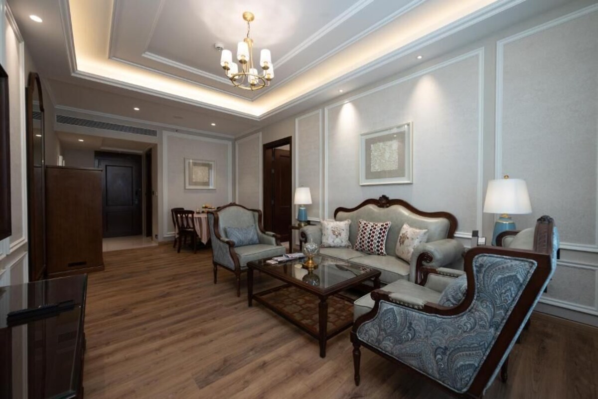 A spacious living room with a sofa, armchairs, a coffee table, and a chandelier.