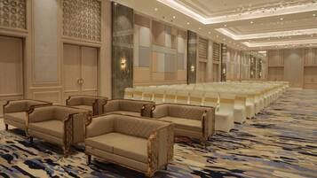 A hotel lobby with a patterned carpet, seating area with sofas and chairs, and a large white block of seating.