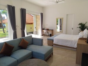 A modern hotel room with a sofa, a bed, a desk, and a view of the outdoors.