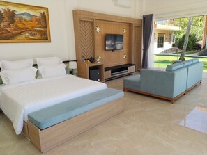 A hotel room with a large bed, a TV, a sofa, and a painting on the wall. - Scampi Indorus Resort (Tejakula)
