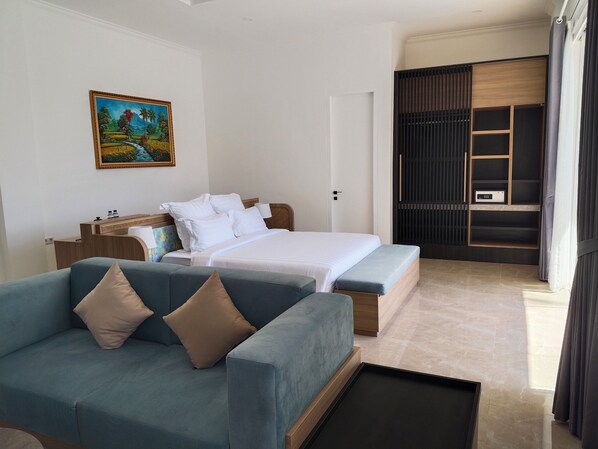 A hotel room with a bed, a sofa, a desk, a painting, and a wardrobe.