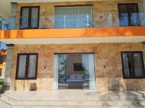 A two-story building with a balcony, a glass door entrance, and a small outdoor seating area. - Scampi Indorus Resort (Tejakula)
