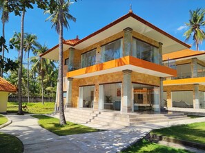 A two-story building with a balcony, surrounded by palm trees and a well-maintained lawn. - Scampi Indorus Resort (Tejakula)