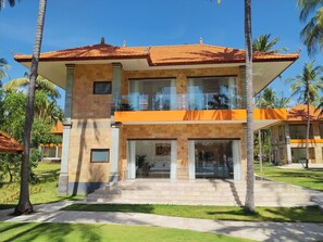 A two-story building with a tiled roof, large windows, and a balcony.