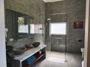 A modern bathroom with a glass-enclosed shower, a marble vanity, and a large mirror.