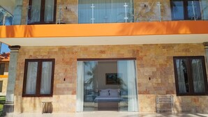 A two-story building with a balcony, a glass door entrance, and a small outdoor seating area.