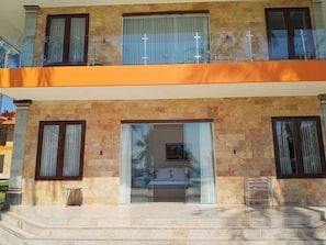 A two-story building with a balcony, a glass door entrance, and a small outdoor seating area.
