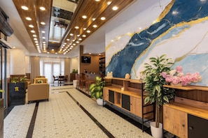 A hotel lobby with a modern design, featuring a large marble wall, wooden reception desk, and a seating area with a sofa and chairs. - Mays By Rich Hotel (Istanbul)