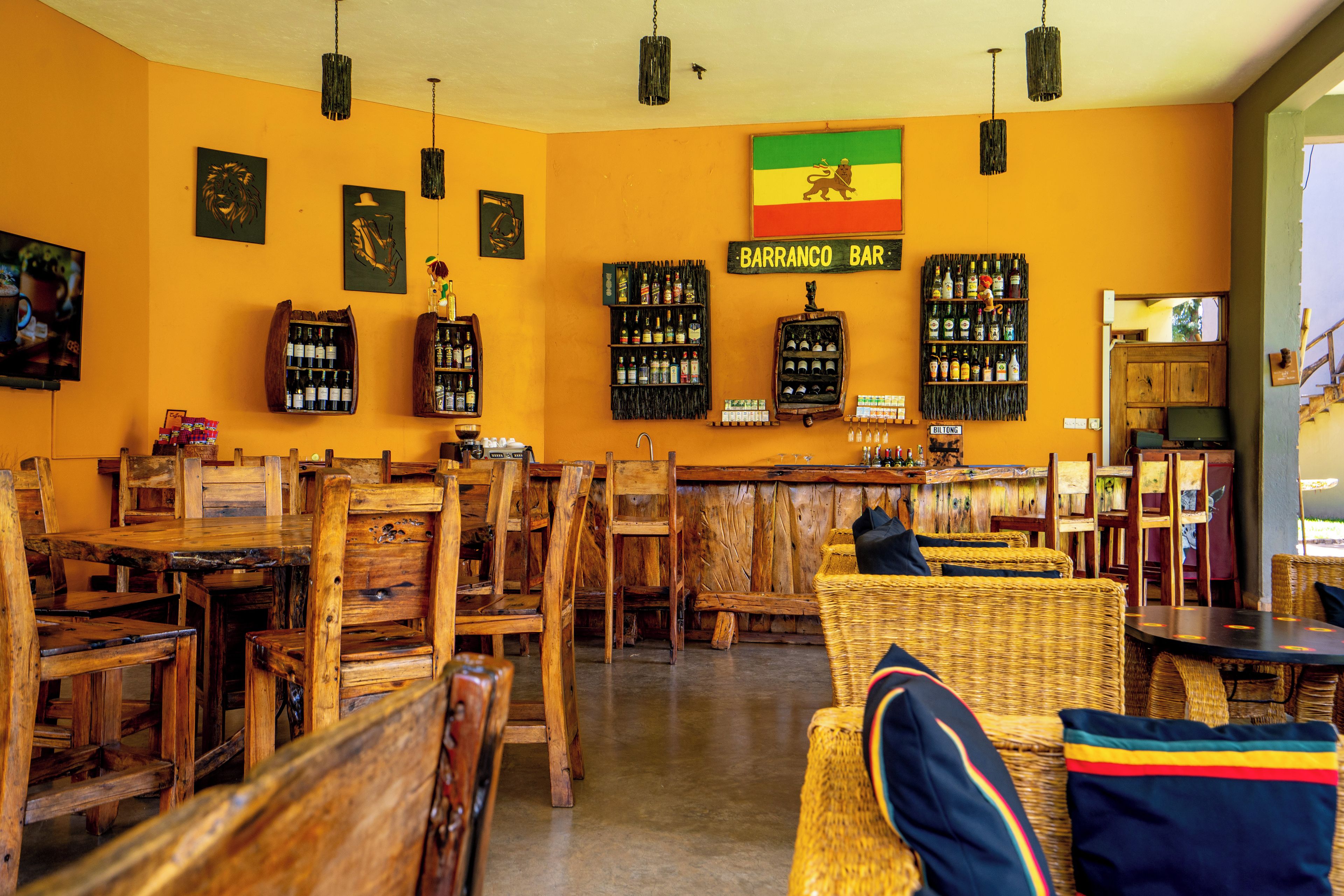 A bar area with wooden furniture and shelves of bottles.