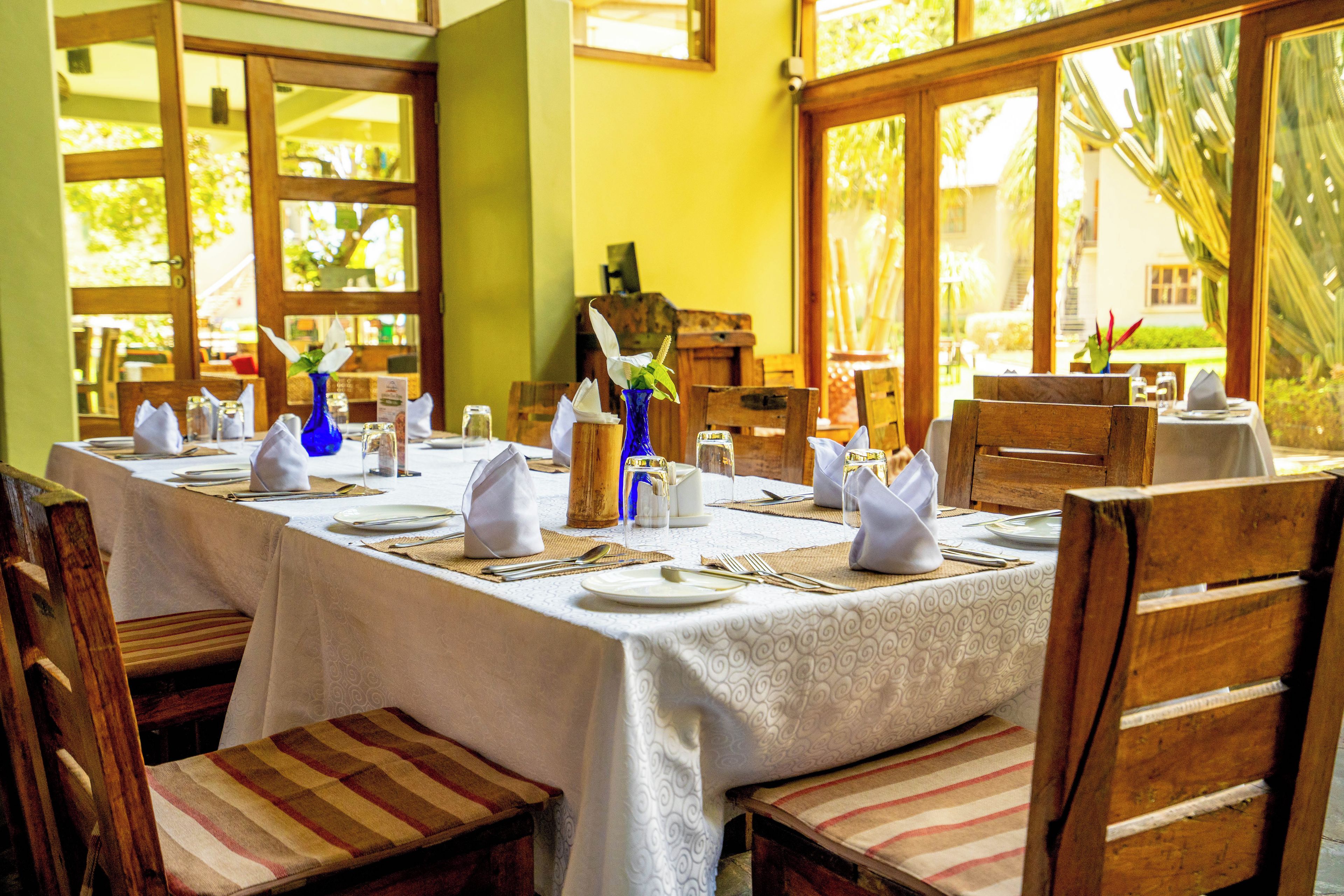Uma sala de jantar com uma mesa comprida posta para refeição, rodeada por cadeiras de madeira.