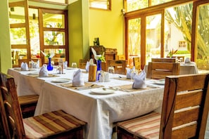 Un comedor con una mesa larga dispuesta para una comida, rodeada de sillas de madera.