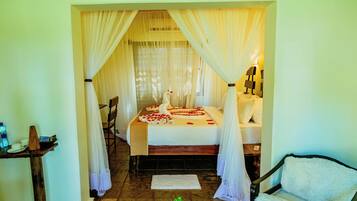 A room with a bed, a chair, a small table, and a potted plant.