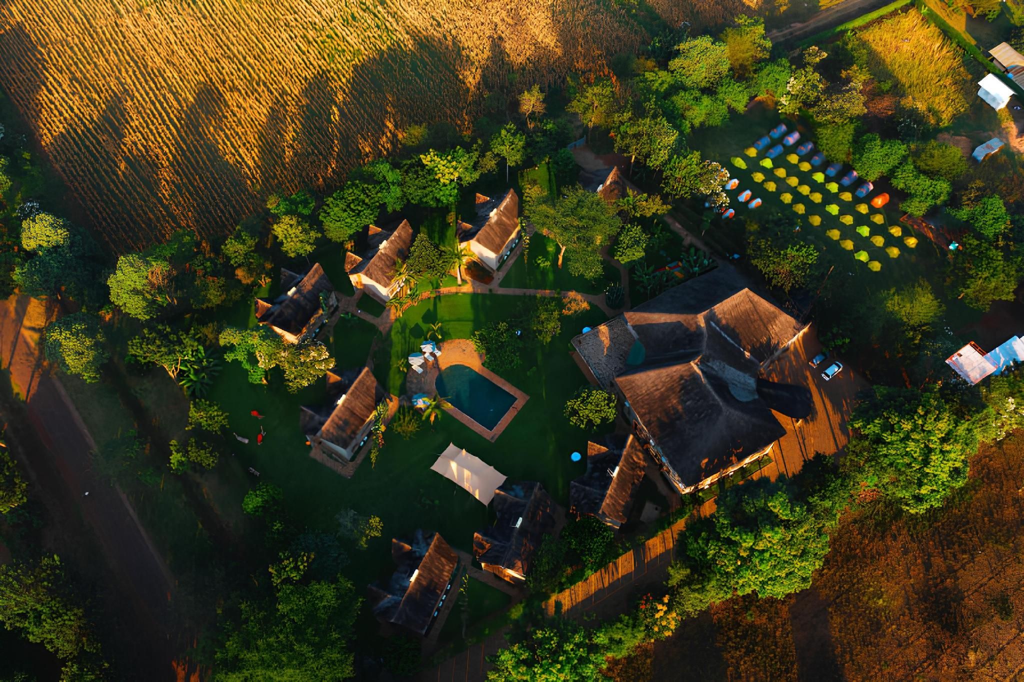 An aerial view of a property with multiple buildings, a swimming pool, and a garden area with boats.
