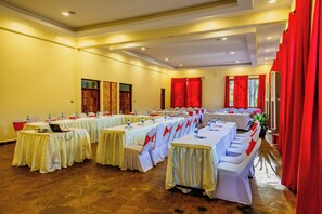 Un salón de conferencias con varias mesas y sillas, equipado con botellas de agua y computadoras portátiles.