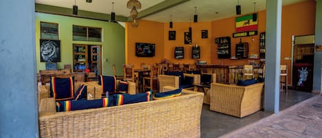 A lobby with wicker sofas, a bar area, and various wall decorations.