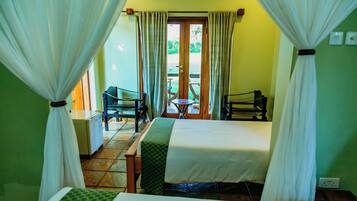 A hotel room with a bed, a chair, a table, and a view of the outside.