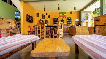 A room with two wooden beds, a central table, and a bar area with shelves of bottles.