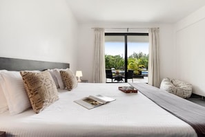 A hotel room with a large bed, a view of the outdoors, and a dining area.
