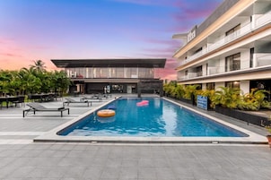 Una piscina con sillas de descanso y un edificio con varios balcones.