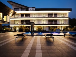 Un hotel de varios pisos con piscina y sillones de descanso.