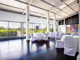 Un espacio interior amplio con ventanas grandes, mesas dispuestas para comer y vistas al exterior con vegetación.