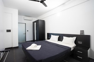 Una habitación de hotel moderna con cama, mesitas de noche, armario y ventilador de techo.