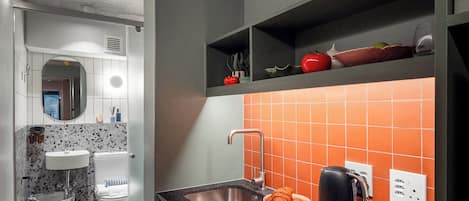 Une cuisine moderne dotée d’un plan de travail noir, d’un évier en acier inoxydable et d’une cuisinière intégrée.