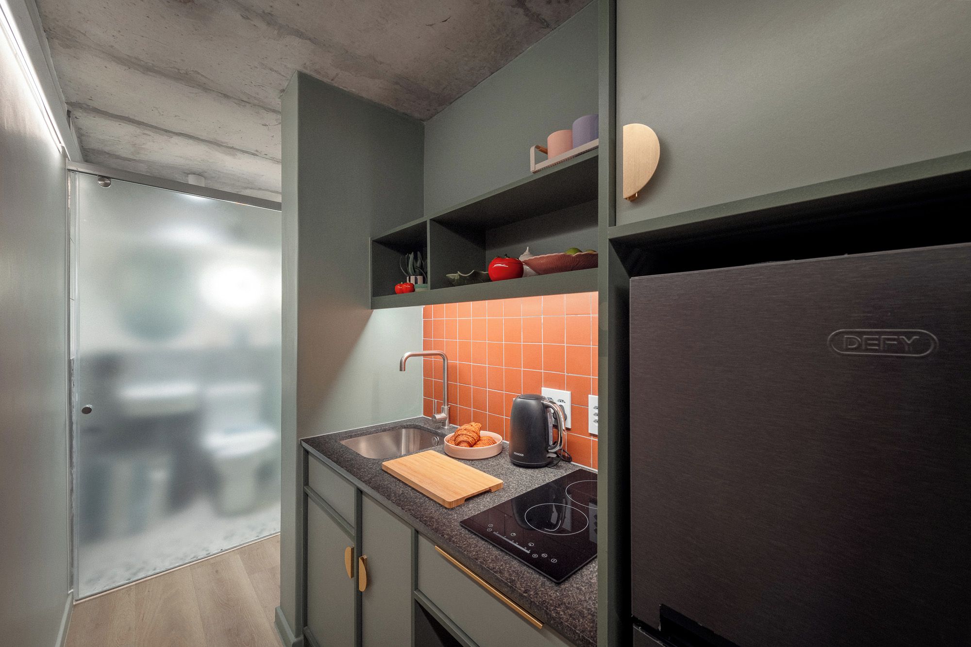 A compact kitchen with a built-in oven, a sink, and a refrigerator.